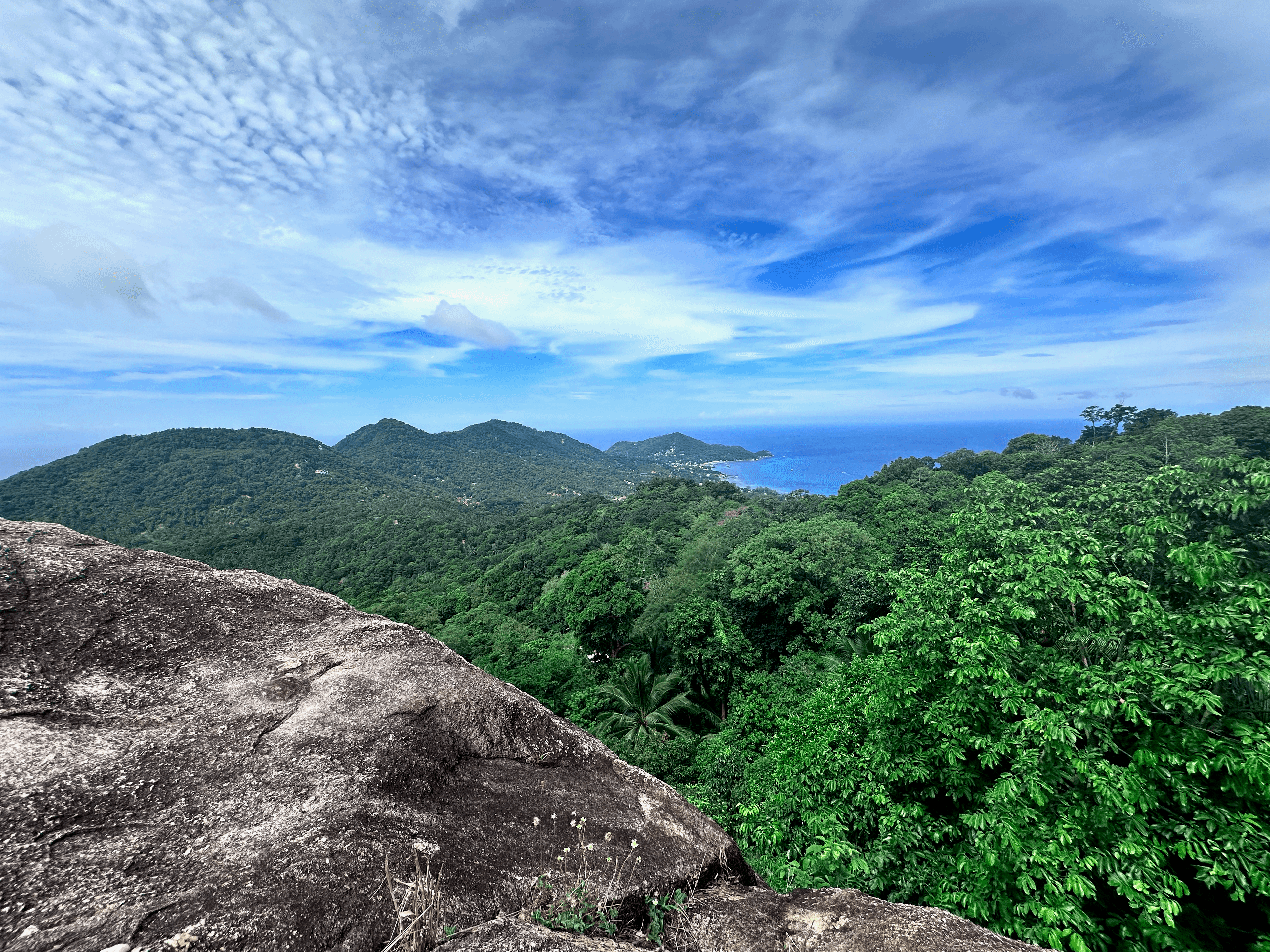 Blue sky, green hills, and rocky viewpoint on Koh Tao Thailand